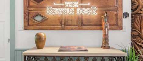A rustic-themed wall decor with the text 'THE RUSTIC BOOK' and a decorative vase on a table.