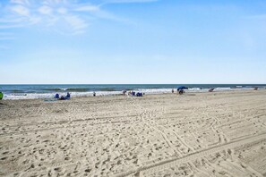 A wide sandy beach with footprints and a few people scattered around. - Brand New!Spacious Oceanview Holiday Villa | 4 Private Ensuites | Steps to the Sand (North Myrtle Beach)