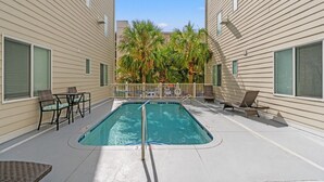 A rectangular pool with a white deck, surrounded by lounge chairs and a small table. - Stunning Golf Spot across from beach, shop, Oceanview, Pool, Elevator (North Myrtle Beach)