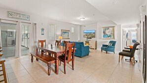 A spacious living area with a dining table, blue sofa, and armchairs. - Stunning Golf Spot across from beach, shop, Oceanview, Pool, Elevator (North Myrtle Beach)