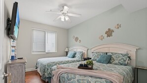 A bedroom with two beds, a ceiling fan, a TV, and a window with blinds. - Stunning Golf Spot across from beach, shop, Oceanview, Pool, Elevator (North Myrtle Beach)