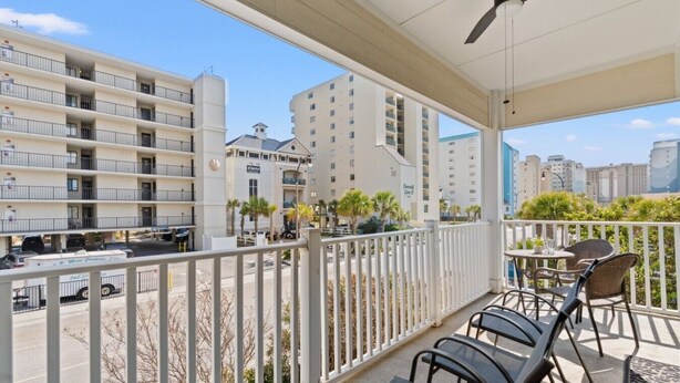 A balcony with outdoor seating, a view of a parking area, and adjacent buildings. - Stunning Golf Spot across from beach, shop, Oceanview, Pool, Elevator (North Myrtle Beach)