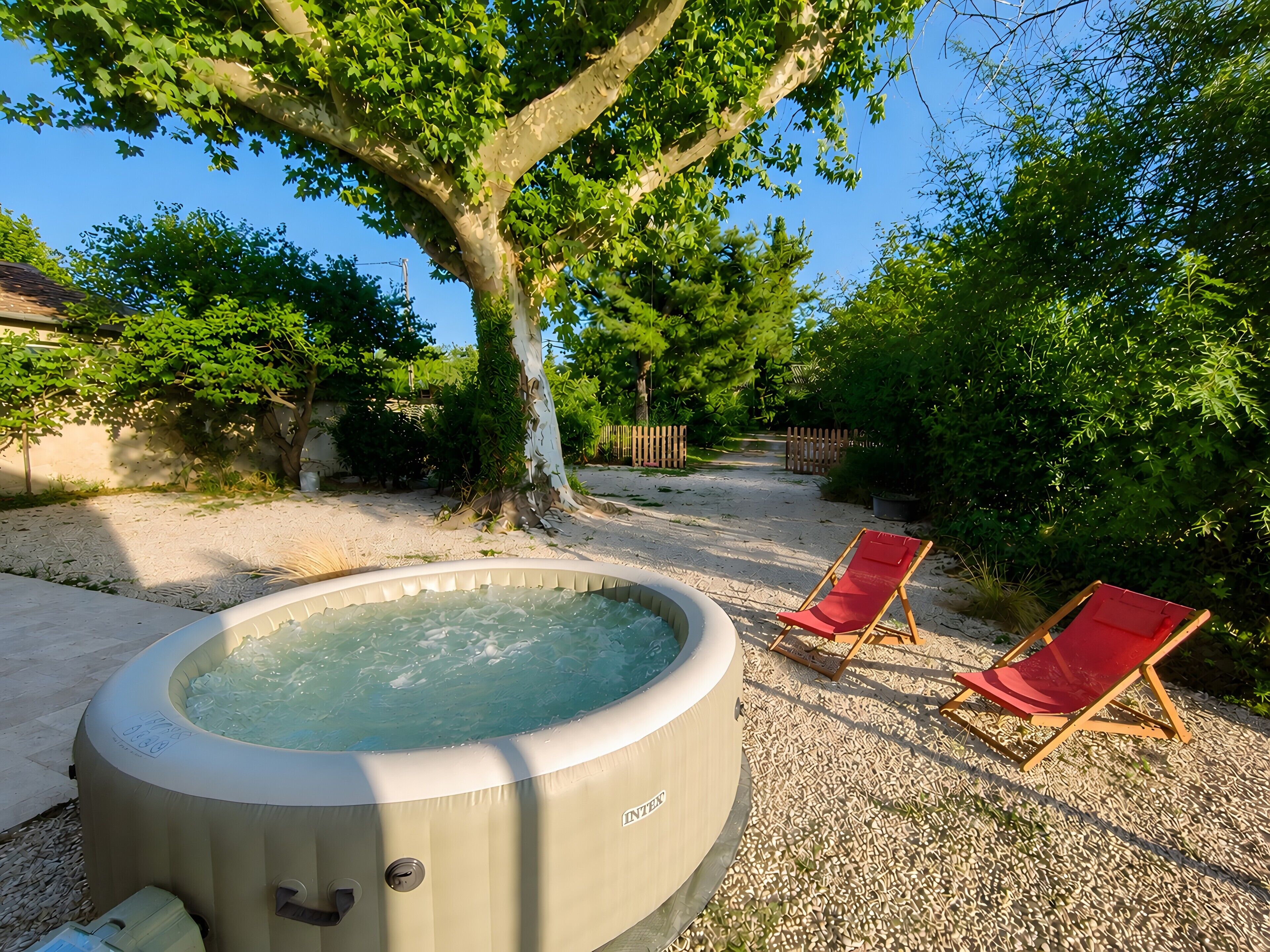Un bain à remous dans un jardin, avec deux chaises longues rouges.