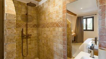 Une salle de bain avec une douche, un lavabo et une fenêtre.