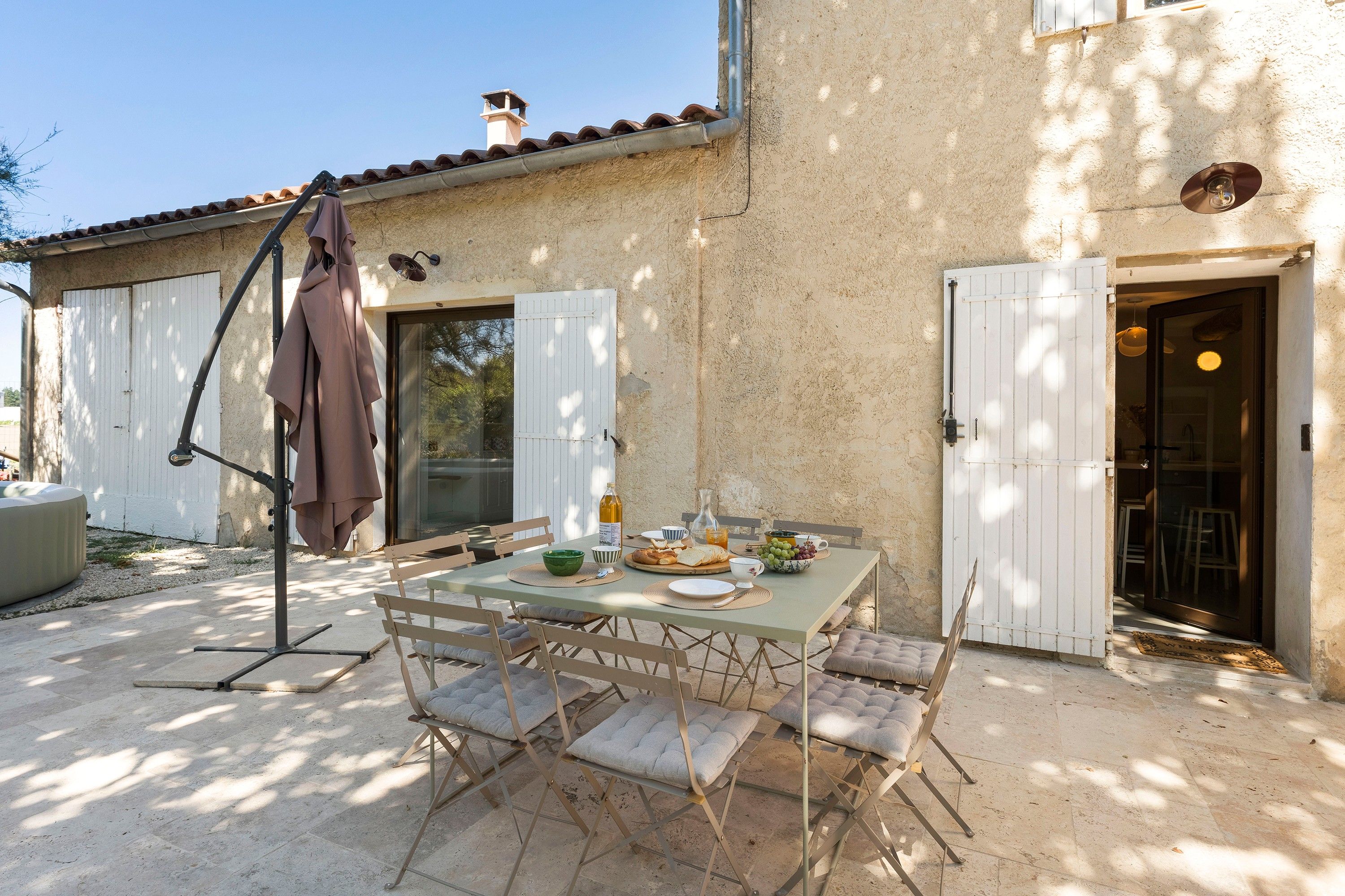 Un espace extérieur aménagé pour prendre les repas, avec une table dressée pour deux personnes, entourée de chaises confortables.