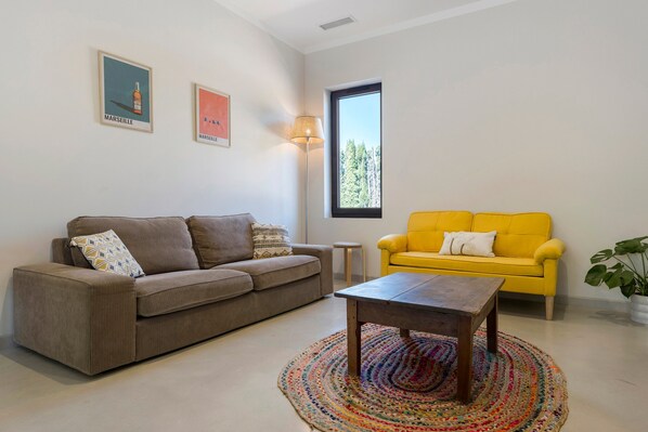 A living room with a brown sofa, a yellow sofa, a coffee table, and a colorful rug.