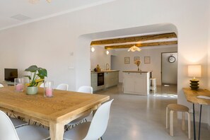 A modern dining area with a wooden table and white chairs, a kitchen in the background, and a cozy atmosphere. - Mas de la Roubine with garden, air conditioning, spa, and Wi-Fi (Châteaurenard)