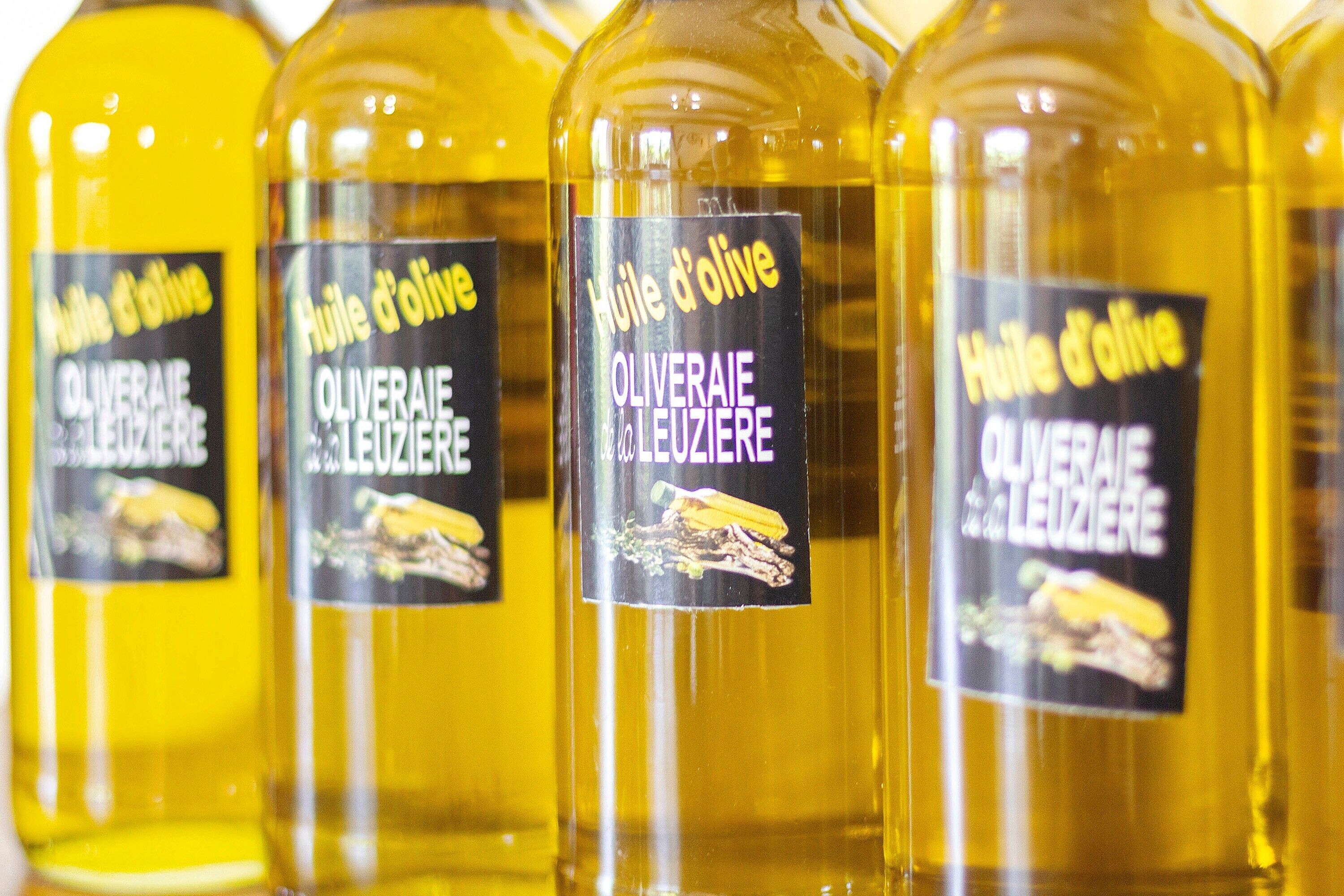 A row of bottles with labels indicating they are olive oil.