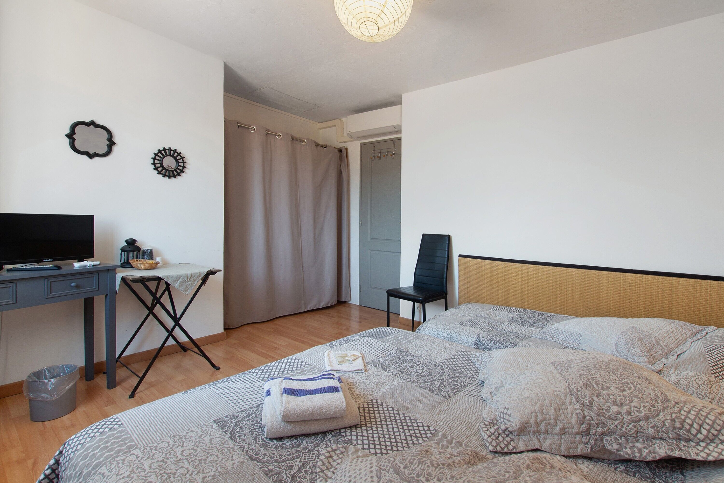Quarto com cama, escrivaninha, cadeira e televisão.