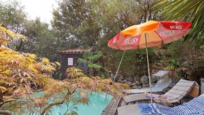 A pool area with lounge chairs and an umbrella.