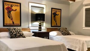 Una habitación de hotel con dos camas individuales, una mesita de noche, una lámpara y dos carteles en la pared.