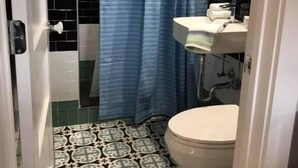 Un baño con inodoro, lavamanos y cortina de ducha.