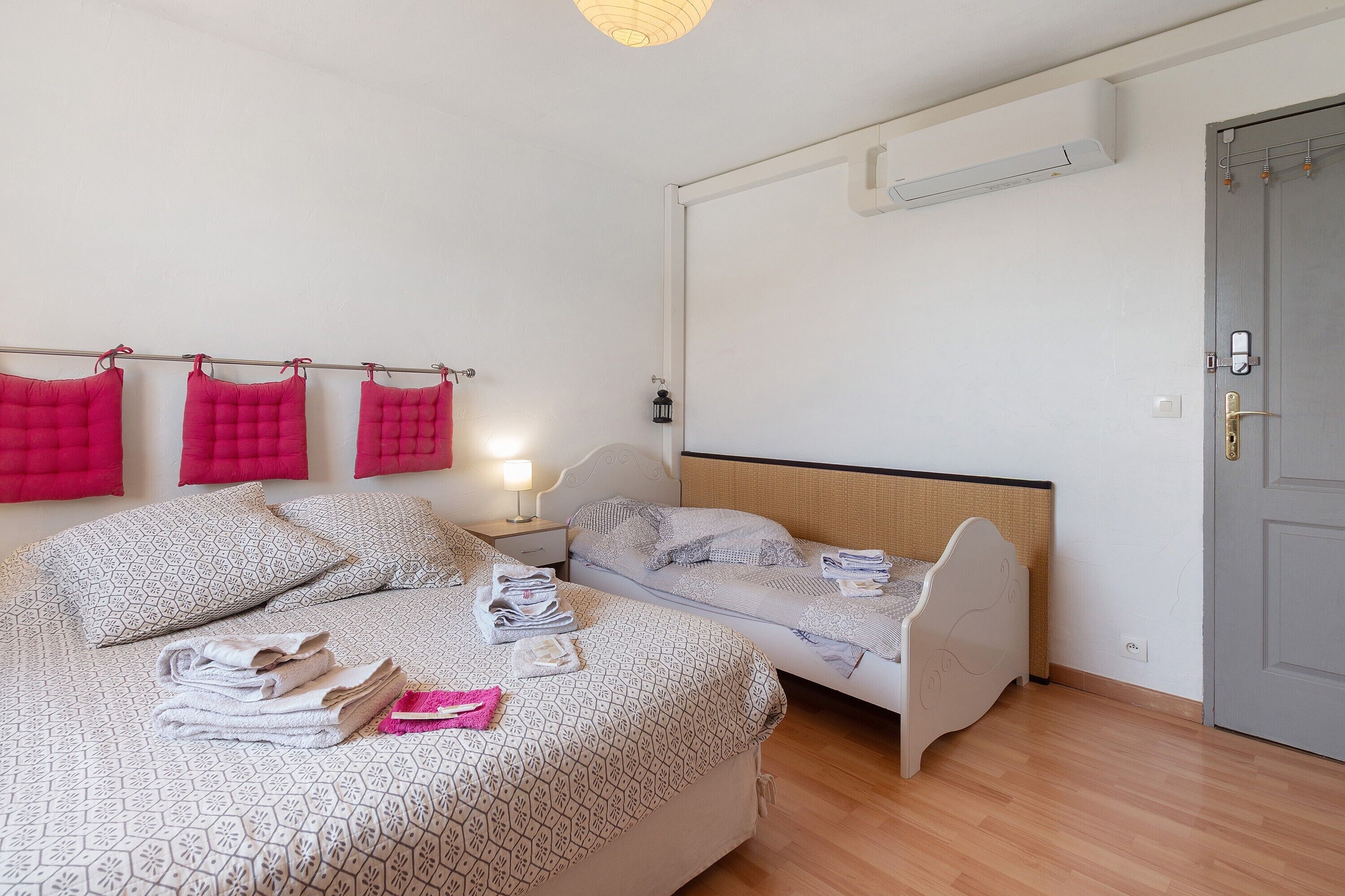 Une pièce comprenant un lit, une table de chevet, une lampe et une porte.