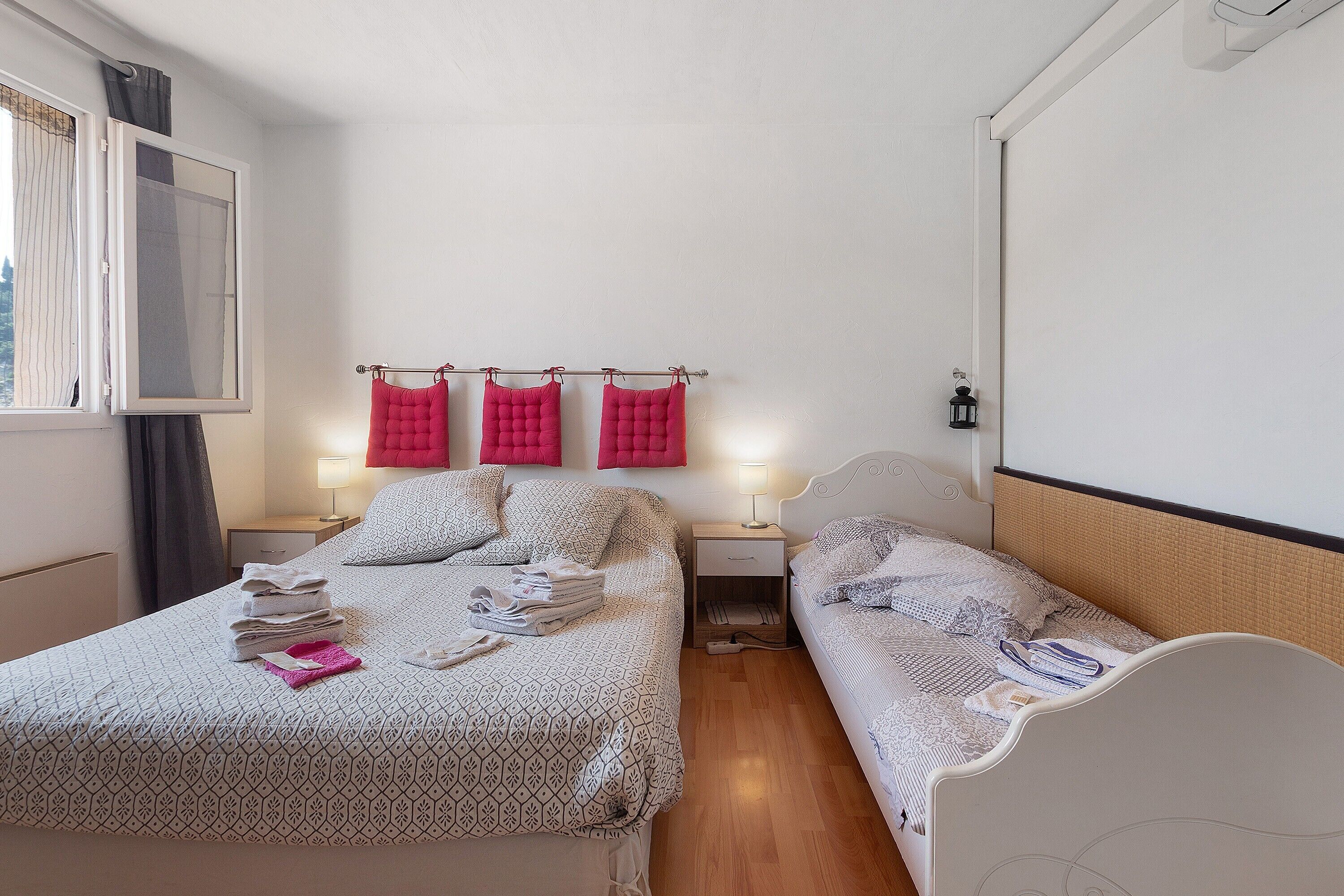 Una camera d'albergo con due letti, un comodino, una lampada e una finestra con tende.
