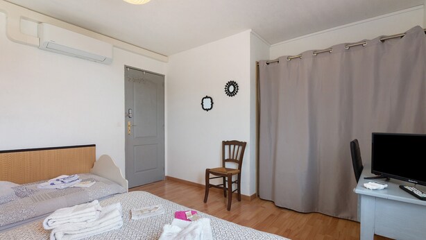 Una habitación de hotel con una cama, una silla, un escritorio y una cortina.