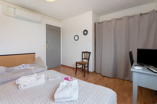 Una habitación de hotel con una cama, una silla, un escritorio y una cortina.