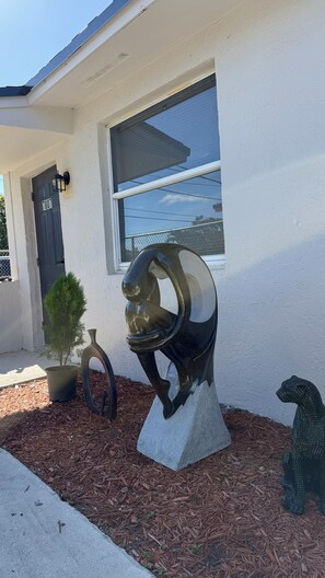Et hus med et vindue, en skulptur og et lille træ.