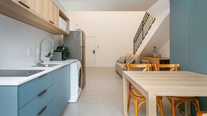 Una cocina moderna con horno integrado, un fregadero y lavavajillas. Hay una zona de comedor con una mesa y sillas de madera.