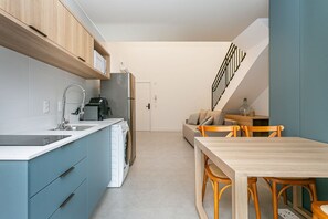Eine moderne Küche mit Einbauofen, Spüle und Geschirrspüler. Ein Essbereich mit Holztisch und Stühlen ist ebenfalls vorhanden.