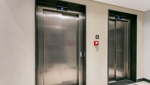 Dos puertas de ascensor con una pantalla digital y un detector de incendios.
