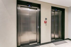 Zwei Aufzugtüren mit digitaler Anzeige und Brandmelder.