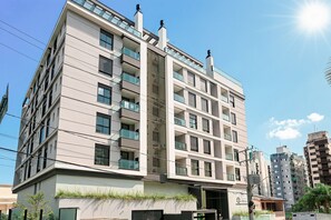 A multi-story residential building with balconies, a flat roof, and a visible entrance. - 350m from Beira-Mar | Pool | Gym #CA103 (Florianópolis)