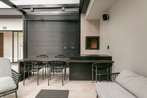 Un espacio al aire libre moderno con una barra de metal para parrilla y sillas.
