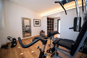 A home gym with exercise equipment, a mirror, and a framed picture on the wall. - Torre with pool and lake-view terraces in Gargnano (Gargnano)