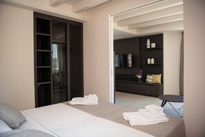 Ein Hotelzimmer mit einem Bett, einer Sitzecke mit Fernseher und einem Kleiderschrank.