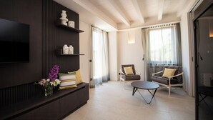A modern living room with a flat-screen TV mounted on the wall, a sofa, a coffee table, and a chair. - Torre with pool and lake-view terraces in Gargnano (Gargnano)