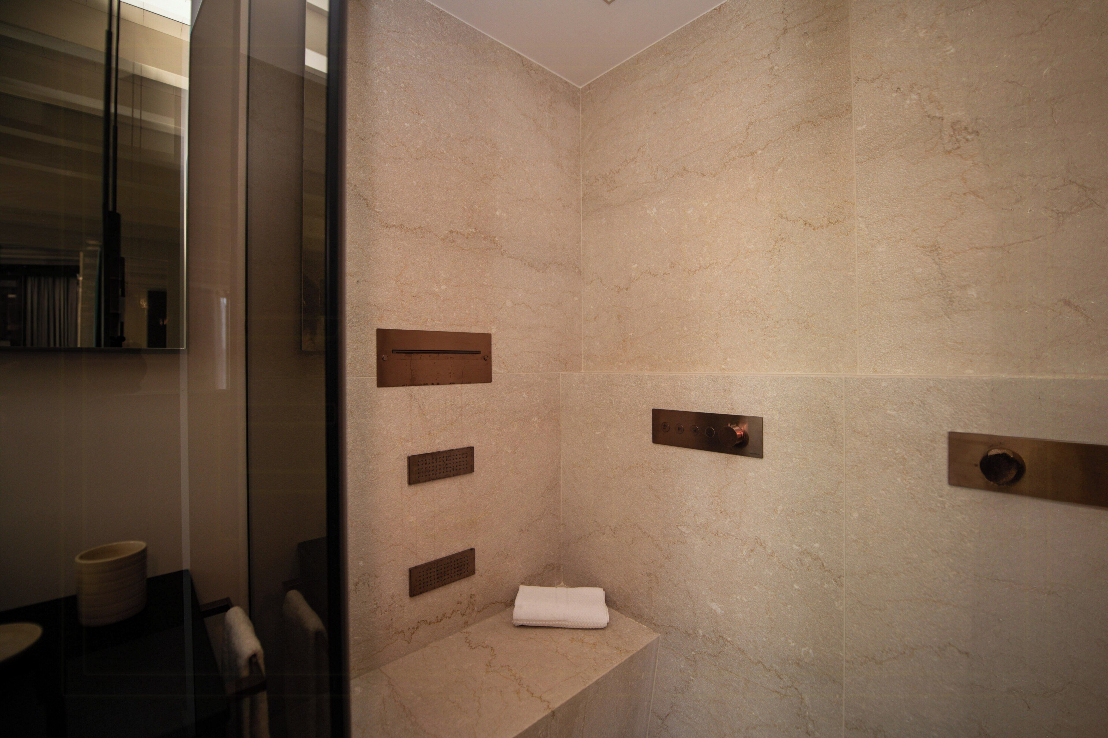 A modern bathroom with a glass partition, a towel rack, and a shower control panel.