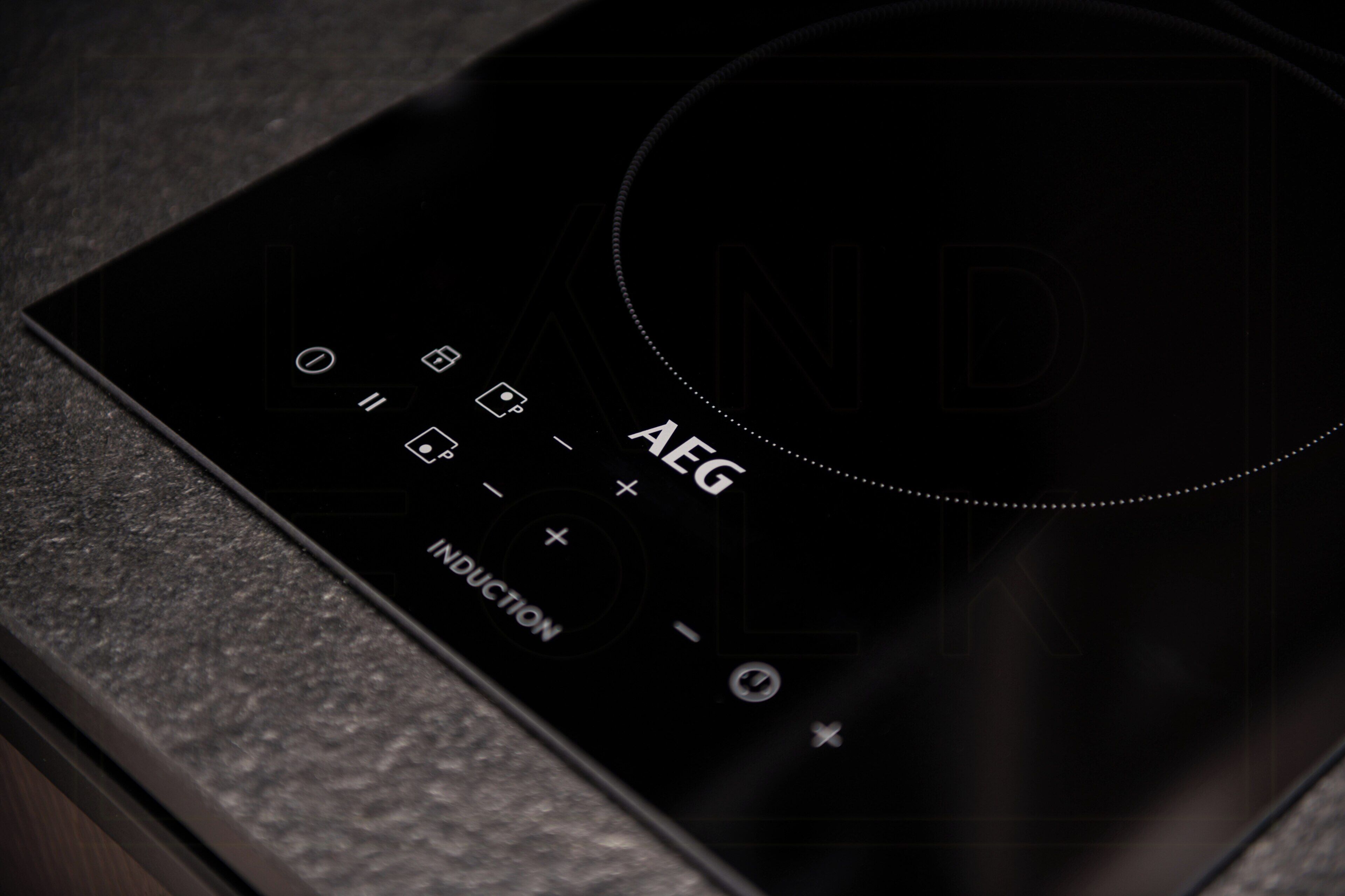 Una cocina de inducción negra con botones de control y una zona de cocción circular.
