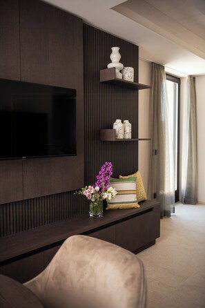 A modern living room with a flat-screen TV mounted on the wall, a dark wood console table with decorative items, and a comfortable seating area. - Torre with pool and lake-view terraces in Gargnano (Gargnano)