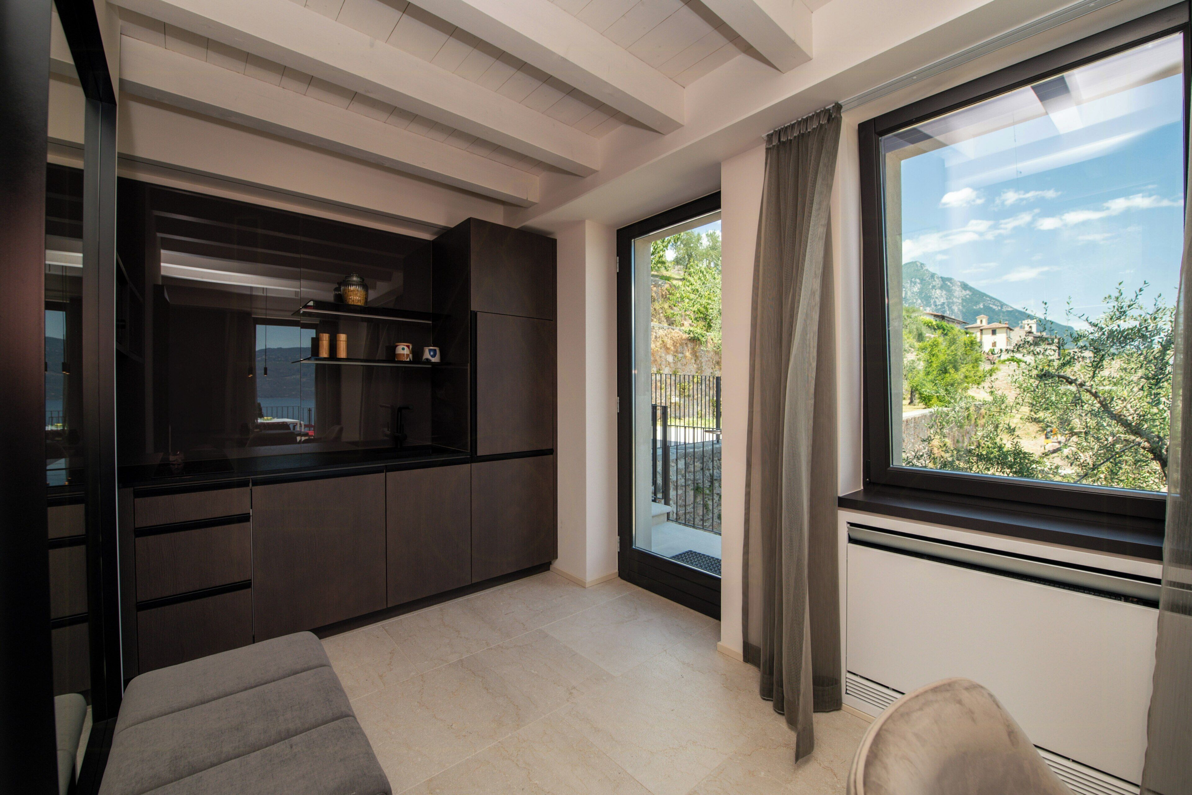 A modern kitchen with dark cabinetry and a large window overlooking a scenic view.
