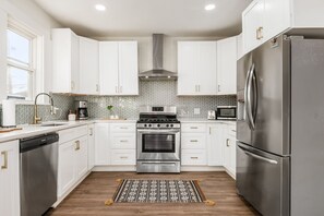 A modern kitchen with white cabinets, stainless steel appliances, and a patterned backsplash. - Spacious & Historic 3BR Near German Village. Fire Pit, Yard, Grill.Veteran-Owned (Columbus)