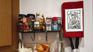 A kitchen shelf with various food items and a framed artwork. - Cute studio apartment on café street close to music venues and camden (London)