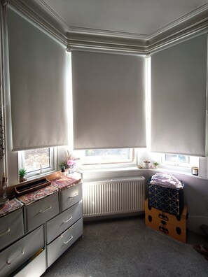 A room with a radiator, a window with a view, a desk with drawers, and a suitcase. - Cute studio apartment on café street close to music venues and camden (London)