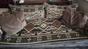 A bed with patterned bedding, a white vase, a small plant, and a wall-mounted green plant. - Cute studio apartment on café street close to music venues and camden (London)