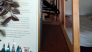 A room with a bed, a wooden table, a hanging plant, a ceiling fan, and a wall-mounted shelf. - Cute studio apartment on café street close to music venues and camden (London)