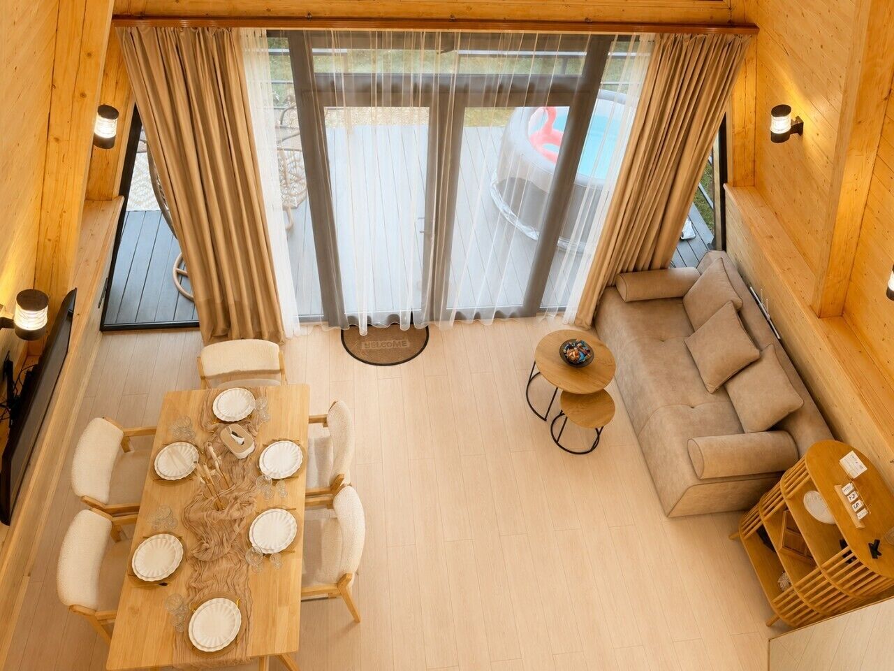 Ein Holzinterieur mit einem Esszimmerstisch für sechs Personen, einer Couch und einem kleinen runden Tisch mit einer Schüssel.