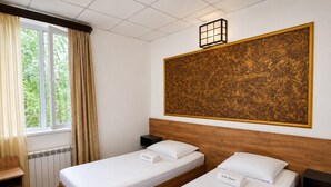 A hotel room with two single beds, a wooden headboard, a large decorative wall piece, a window with curtains, and a radiator. - Pine Garden Boutique Hotel and Pool in Stepanavan (Stepanavan)