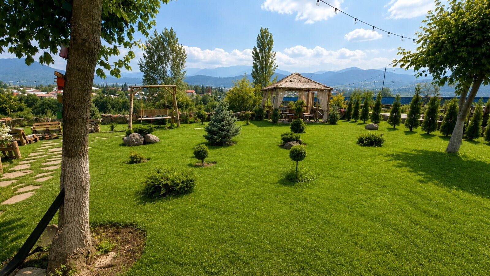 Un giardino curato con un gazebo, prato ben tagliato e diverse specie di alberi.