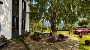 A modern house with a stone pathway, a red vintage car, and a well-maintained garden. - Pine Garden Boutique Hotel and Pool in Stepanavan (Stepanavan)