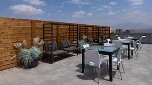 Un espace extérieur aménagé avec des tables et des chaises, une clôture en bois et des plantes en pot.