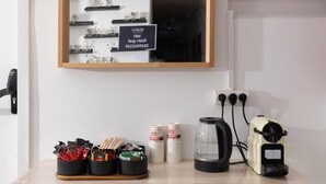 Une table avec une machine à café, une bouilloire et des tasses empilées.