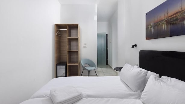 Une chambre d’hôtel moderne avec un grand lit, une armoire en bois, une chaise et un tableau au mur.