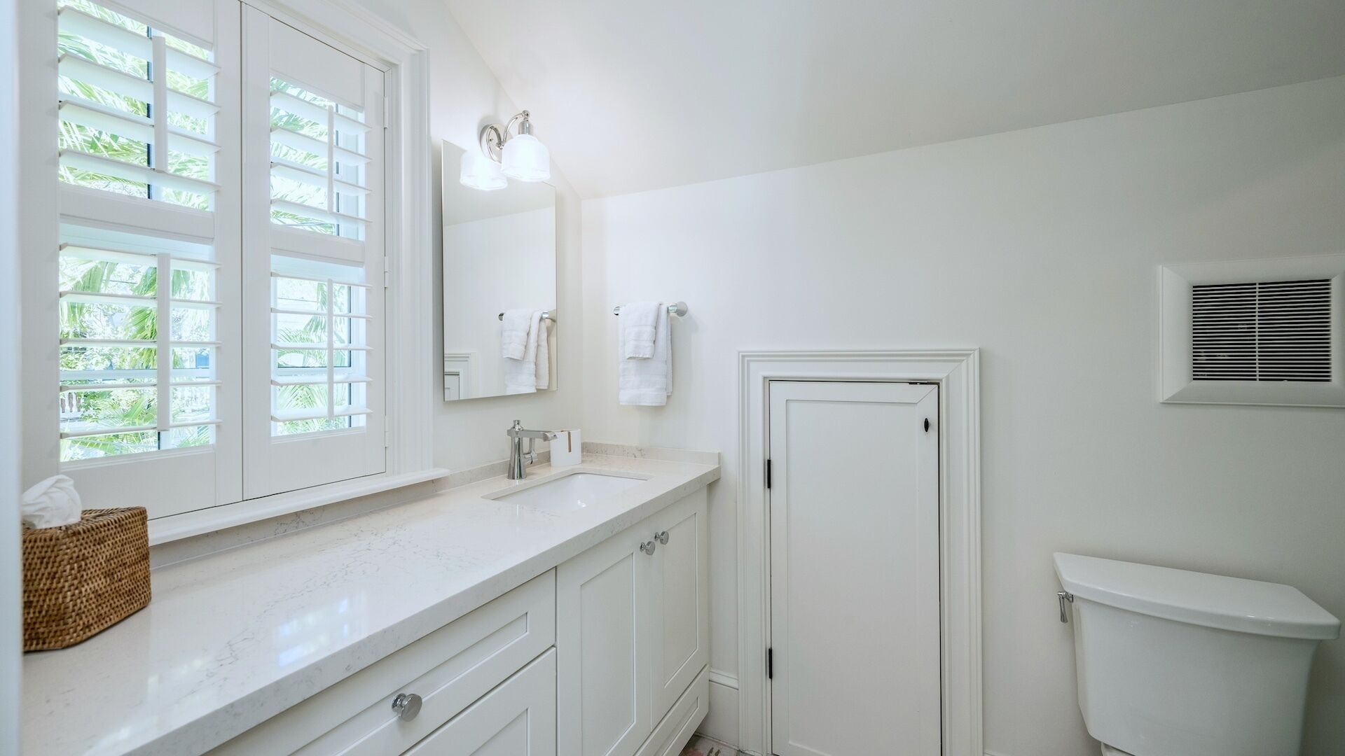 A bathroom with a white vanity, a mirror, a towel rack, and a toilet.