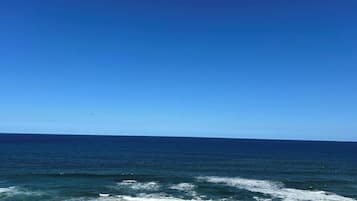 A view of the ocean from a balcony with a clear sky.