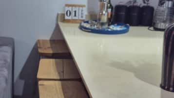 A long wooden table with benches, a small clock, and a decorative item on the wall.