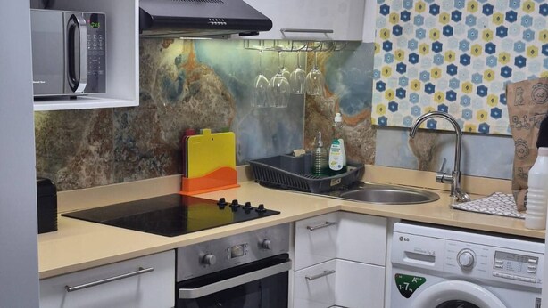 Eine kleine Küche mit Mikrowelle, Backofen, Waschmaschine und Spüle.